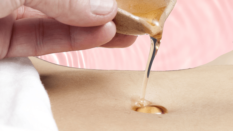 close up of pouring oil into a belly button